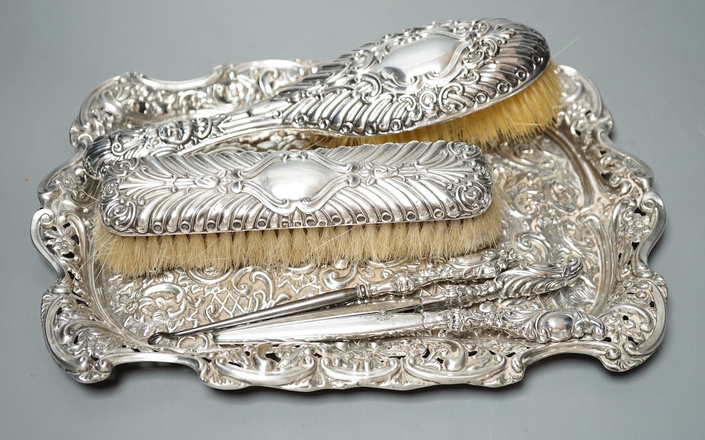 A late Victorian repousse silver dressing table tray, Birmingham, 1898, 30.5cm, together with tow silver mounted brushes, mounted button hook and glove stretchers.